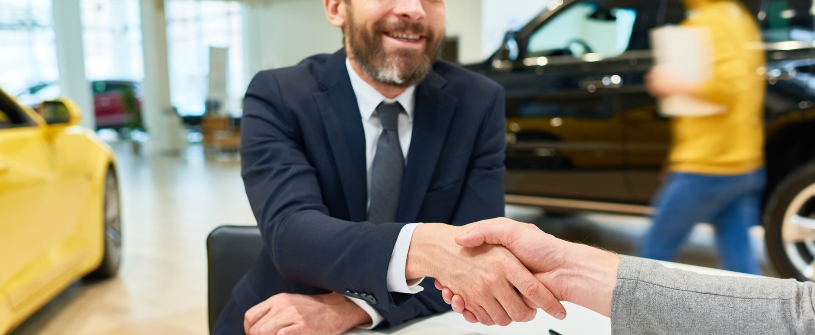 A customer shaking hands with a salesperson while buying a used car in PA 