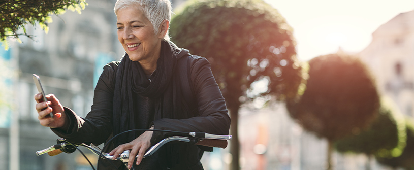 A customer uses the PSECU mobile app from her phone while riding a bike