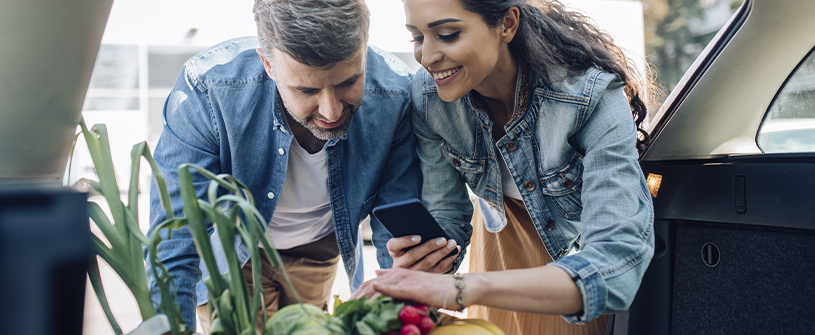 Man and woman with groceries looking at phone